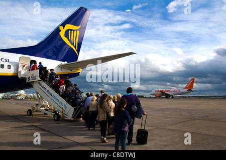 Passagieren Warteschlange ein Ryanair Boeing 737-800 Flugzeug wie ein Easyjet Flugzeug an Bord landet Stockfoto