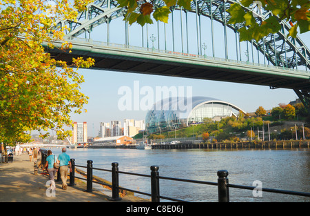 Paar auf Newcastle Quayside unter dem Tyne Bridge. Gateshead Salbei Konzertsaal in Ferne. Newcastle Upon Tyne, England. UK Stockfoto