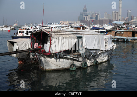 marode Hausboote in Hong Kong Victoria Harbour, Hong Kong, China. Wolkenkratzer zeigen am Horizont hinter. Stockfoto