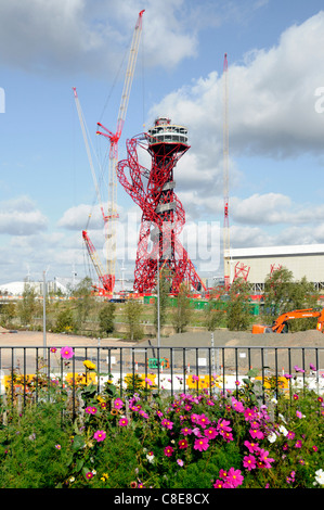 Blütenpracht entlang Greenway Pfad mit Teil von London 2012 Olympic Baustelle Krane in Arbeit auf ArcelorMittal Orbit Turm Stratford Stockfoto