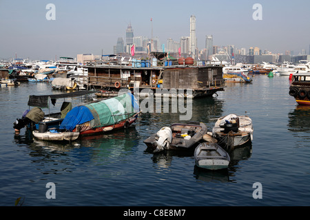 marode Angeln und Hausboote in Hong Kong Victoria Harbour, mit Wolkenkratzern am Horizont hinter, Hong Kong, China Stockfoto