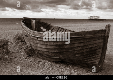 Schwarz / weiß Foto eines Bootes auf Brighton Beach mit den verbrannten, Pier West im Hintergrund Stockfoto