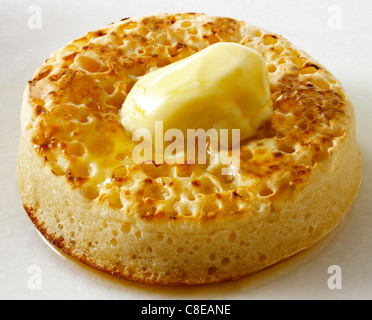 Einzelne traditionelle hot Butter crumpet schließen bis auf einem weißen Hintergrund, mit zerlassener Butter bereit zu essen Stockfoto