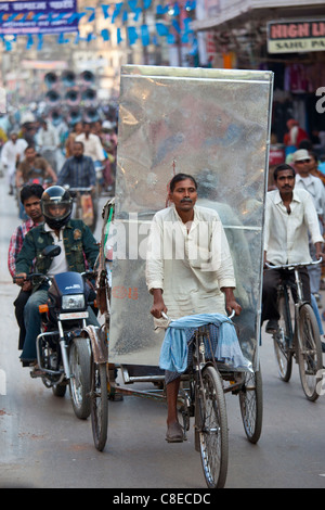 Indischer Mann fahren Rikscha mit schweren Last im Straßenbild in Stadt Varanasi, Benares, Nordindien Stockfoto