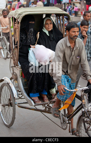 Muslimische Frauen reisen mit Rikscha in überfüllten Straßenszene in Stadt Varanasi, Benares, Nordindien Stockfoto