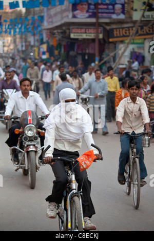Muslimische Frau mit Hijab Burka Schleier über Kopf und Gesicht-Zyklen in der Straße in Stadt von Varanasi, Benares, Nordindien Stockfoto