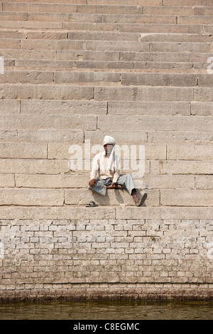 Hindu Mann sitzt auf Stufen des Chet Singh Ghat auf die Ganges-Fluss in der Heiligen Stadt Varanasi, Indien Stockfoto