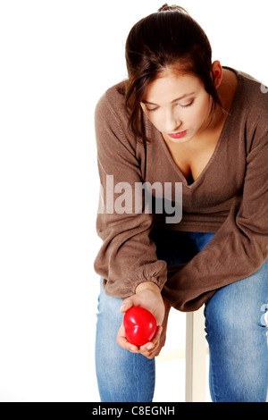 Allein Mädchen in Depression auf einem Stuhl sitzend und Herz in der Hand halten. Stockfoto