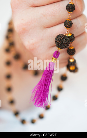 Mans Hand mit indischen Rudraksha / Japa Mala Gebet gegen weiße Perlen
