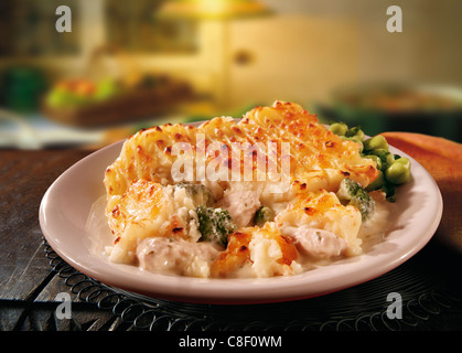 Traditionelle Huhn und Gemüsekartoffel Pie Mahlzeit serviert mit neuen Kartoffeln auf einem Teller in einer rustikalen, heimeligen Küche Stockfoto