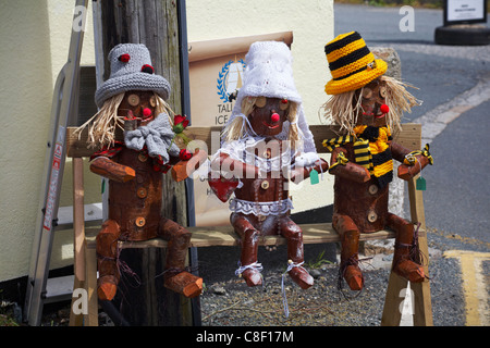 Aus Holz geschnitzte Figuren verkleidet, setzte auf Bank außerhalb Shop in Charlestown, Cornwall Stockfoto
