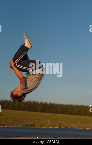 Teenager Springen auf einem Trampolin lachen und dabei Saltos auf einem Sommer Abend Stockfoto