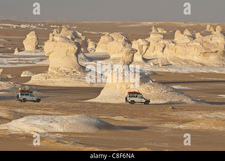 Jeeps, vorbei an den Wind erodiert Skulpturen von Kalzium reiche Felsen in der Weissen Wüste in der Nähe von Bahariya, Ägypten, Nordafrika Stockfoto