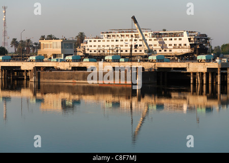 Ein Teil des Nil Flusses mit cruise Boot im Trockendock, mit Kränen und Gebäude spiegelt sich in der Flaute Wasser, Ägypten Stockfoto