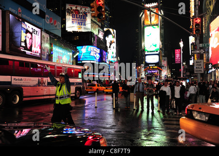 Nachtaufnahme gelbe Jacke Polizist Handzeichen den Verkehr West 45th Street 7th Avenue, nass Neon Times Square in New York Stockfoto