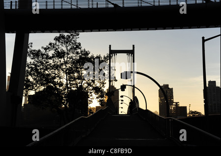 Herbst Sonnenaufgang Silhouette, in Richtung Roosevelt Island, East River Esplanade Steg, über Franklin D.Roosevelt Drive, New York Stockfoto