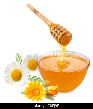 Honig gießt mit Stöcken in ein Glas. Blumen sind in der Nähe. Isoliert auf weißem Hintergrund. Stockfoto