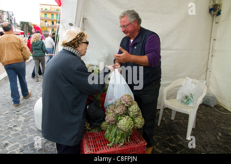 Ältere Frau Artischocken im Stall auf Straßenmarkt Messe Italien italienische Mittelmeer kaufen Stockfoto