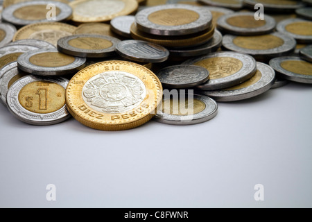 Eine mexikanische 10 Pesos Münze Spot beleuchtet unter einem Haufen von anderen modernen mexikanischen Peso-Dollar und Cent Münzen. Stockfoto