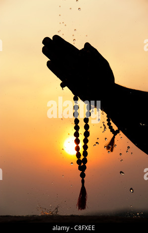 Mans Gebet Hände halten indischen Rudraksha / Japa Mala Gebetskette. Silhouette Stockfoto