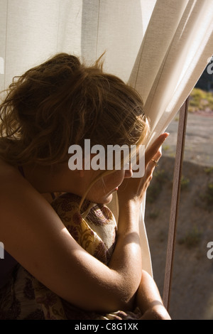 Junge Frau aus dem Fenster schauen. Stockfoto