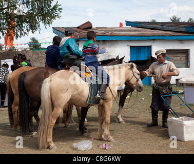 Die Tsetserleg Naadam drei jungen auf dem Rücken der Pferde genießen Sie einen Kebab bei einem lokalen Händler gekauft. Stockfoto