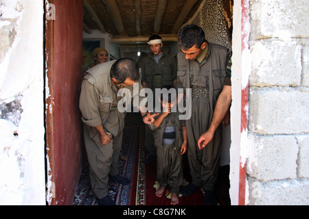 Kurdische Kämpfer der People's Defence Forces HPG dem militärischen Flügel der Kurdischen Arbeiterpartei PKK-Führer ein uniformierter Kind den Sieg in der Quandil Berge zu markieren, in der Nähe der iranischen Grenze im Norden des Irak Stockfoto