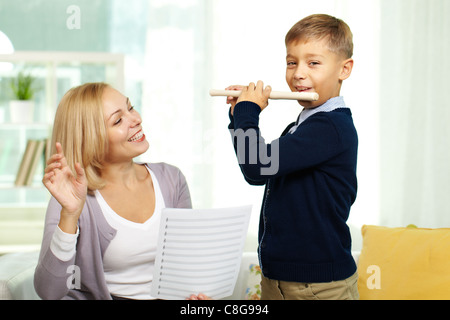 Porträt der glückliche Schüler das Flötenspiel mit Tutor auf Hintergrund Stockfoto