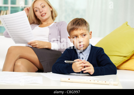 Porträt von fleißigen Schüler mit Noten auf Papier in der Nähe von und seinem Lehrer auf Hintergrund Stockfoto