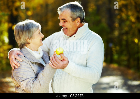Foto von amourösen gealterter Mann und Frau hält Apfel und sahen einander Stockfoto
