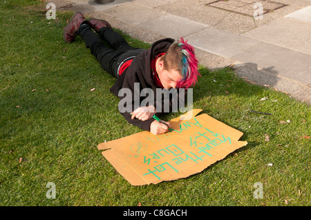 London zu besetzen. Finsbury Square.A Mitglied der Protest-Camp macht ein Schild mit der Aufschrift "Hocken die Menge, es ist uns sowieso" Stockfoto