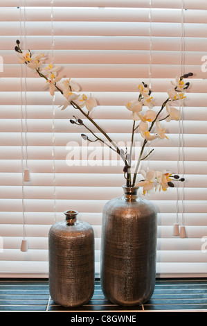 Flasche Vasen mit Kunstblumen auf einem Fensterbrett Stockfoto