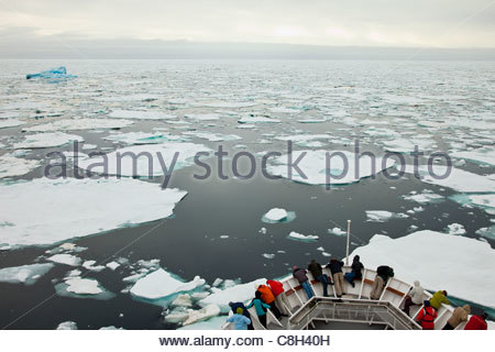 Touristen suchen im Packeis vom Bug eines Kreuzfahrtschiffes. Stockfoto