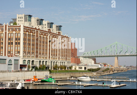 Umgewandelte Eigentumswohnungen entlang den alten Hafen von Montreal mit Jacques Cartier Brücke im Hintergrund Stockfoto