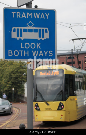 Manchester Metrolink Straßenbahn bewegten Vergangenheit "Look Both Ways" Zeichen durch Salford Quays, Manchester, Lancashire, UK Straßenbahn. Stockfoto