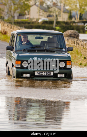 Mann fährt Range Rover durch überfluteten Landstraße in Nordirland auf Dienstag, 25. Oktober 2011. Stockfoto