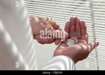 Leben mit einem knappen Budget, Münzen zählen die Pfennige, während einer Rezession die Runden zu kommen, Nahaufnahme der Hände Stockfoto