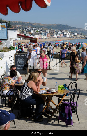 Lyme Regis Strandpromenade ein Dorset-Ferien-Resort im Westen des Landes England UK Urlauber am Strandcafé sitzen Stockfoto