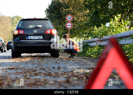 Panne, Platten Reifen. Frau ändert einen Reifen eines Autos auf einer Autobahn, eine Warnweste zu tragen. Stockfoto