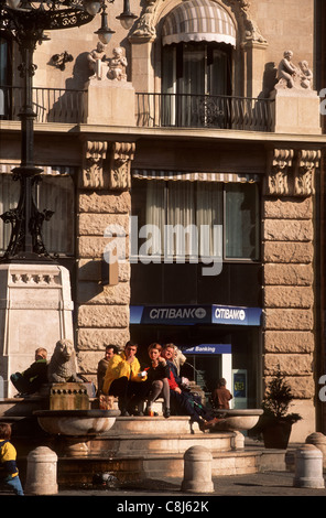 Budapest, Ungarn. Personen (paar) sitzen auf Stufen des Brunnens McDonalds Essen; Citibank Geldautomaten hinter. Stockfoto