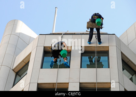 Glasreiniger Arbeitnehmer Abseilen vom Dach nach unten von Office Block Spiegelungen in Glas London England Großbritannien Stockfoto