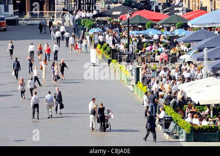 Massen von Büroangestellten Essen bei Beschäftigten im hoteleigenen Restaurant mit bunten Sonnenschirmen West India Quay Canary Wharf im Osten Londons Docklands Tower Hamlets GROSSBRITANNIEN Stockfoto