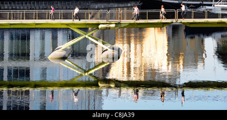 Menschen zu Fuß über North Station Steg und Reflexion über die West India Quay in Canary Wharf Isle of Dogs Tower Hamlets, East London England Großbritannien Stockfoto