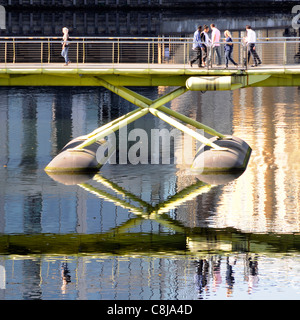 Menschen zu Fuß über North Station Steg und Reflexion über die West India Quay in Canary Wharf Isle of Dogs Tower Hamlets, East London England Großbritannien Stockfoto