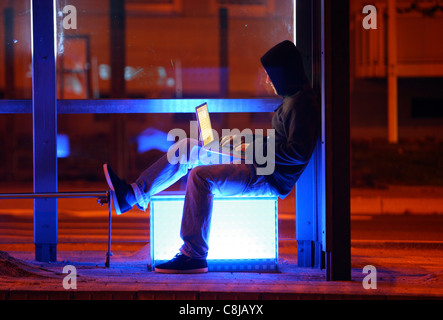 Computer-Benutzer, Hacker, verschwörerisch, außerhalb, Bushaltestelle, mit einem Laptop sitzt. Symbolbild, Computer-Internet-Kriminalität. Stockfoto