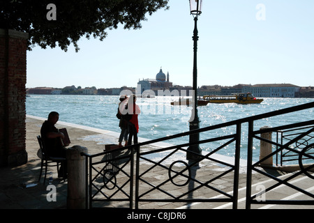 2 Frau, Blick auf die Lagune, während Straßenmusiker spielt Akkordeon, Venedig Italien Stockfoto