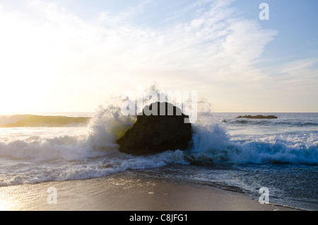 Wellen, die Runde ein Granitblock an einem Strand entlang Route 1, Kalifornien Stockfoto