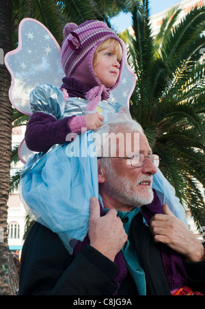 Nizza, Frankreich, Familien mit Kindern in Kostümen, Mädchen auf den Schultern des Mannes, genießen jährliche Karnevalsveranstaltungen auf der Straße, Promenade des anglais france Stockfoto