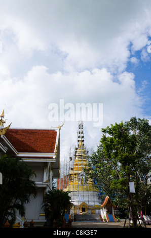 Goldene Stupa restauriert hat Gerüst um es mit Wolken & kunstvolle Tempel bauen auf linken Seite am thailändischen buddhistischen Tempel Stockfoto