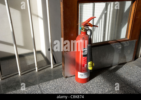 Feuerlöscher, hält eine Brandschutztür öffnen am oberen Rand eine Reihe von Treppen in einer alten Fabrik-Lager-Einheit Stockfoto